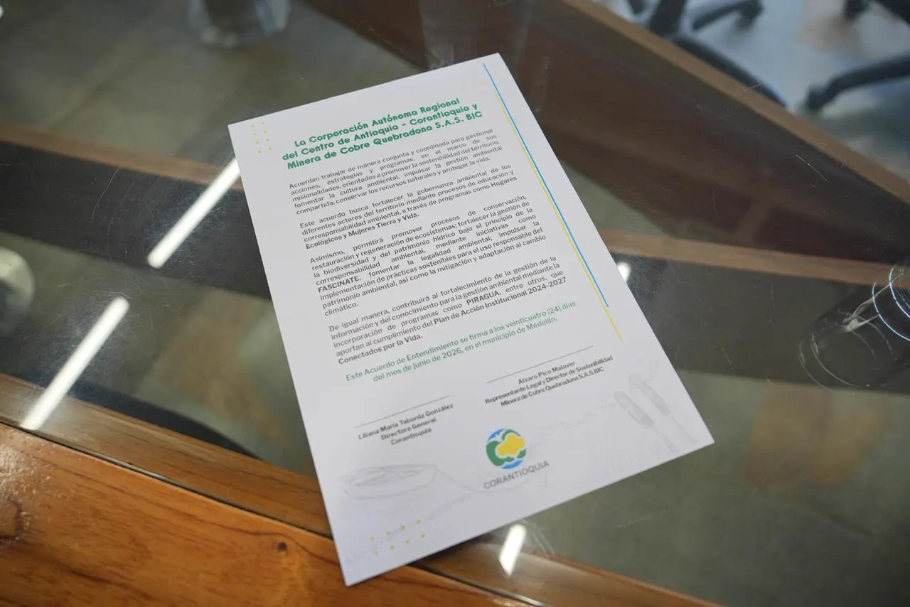 Documento impreso del acuerdo, con el logo de Corantioquia, sobre una mesa de vidrio.