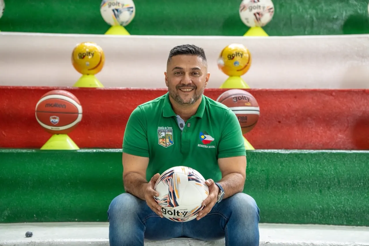 César Zapata, con camiseta verde, sentado en unas graderías sostiene un balón de fútbol de salón.